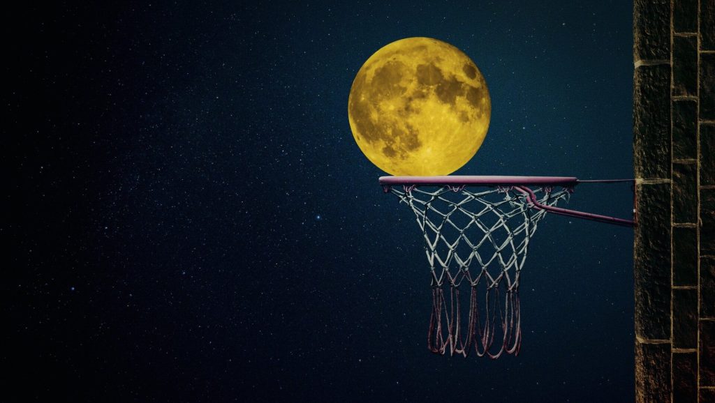 La luna piena appoggiata su un canestro da basket nel cielo stellato