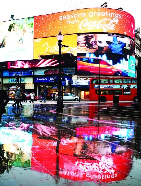 Piccadilly Circus a Londra con i grandi schermi pubblicitari riflessi sull’asfalto bagnato